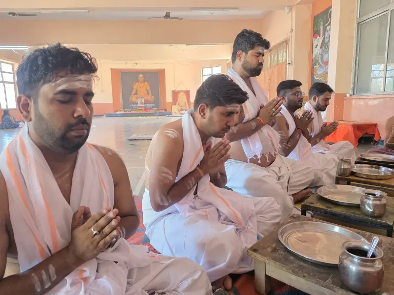 Devotees in white dhotis with folded hands during the mantra jaap