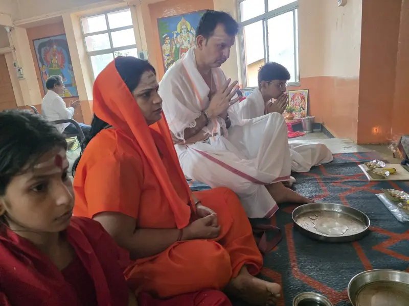 A couple seated with Guruji in the puja hall